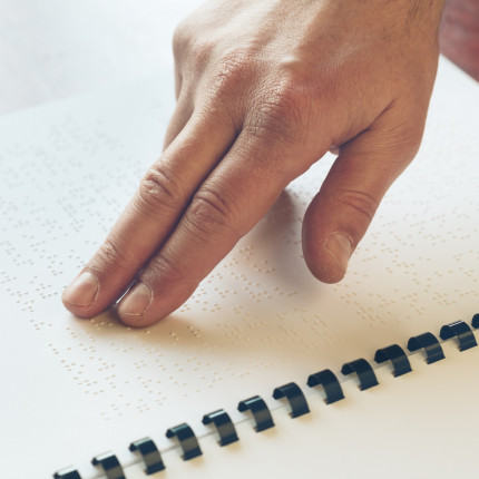 Scottish Braille Press close up photo of a person reading braille