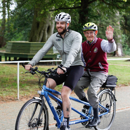 Veteran waves while tandem cycling with Vie Velo at Linburn Centre