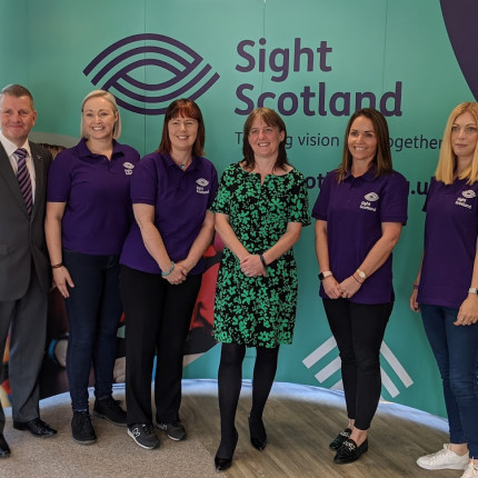 Maree Todd MSP stands with staff from the Family Wellbeing Service in front of a Sight Scotland banner