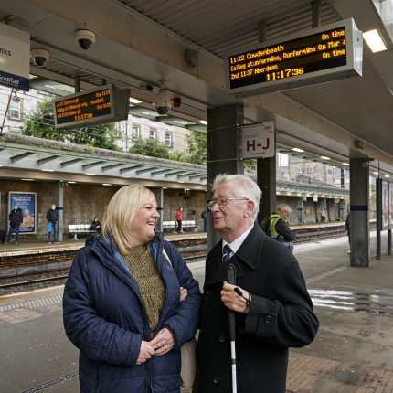 Two people chat at a train station