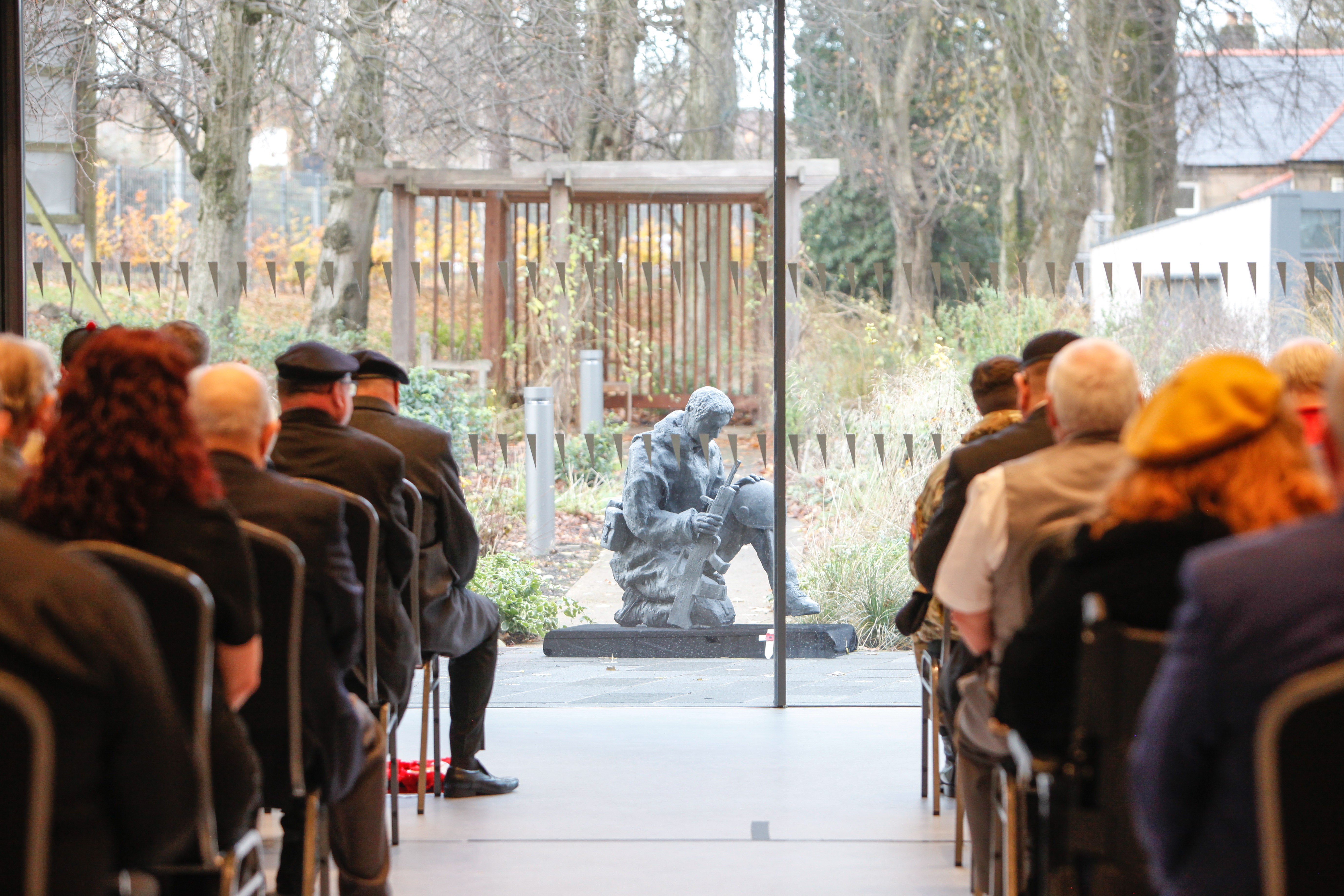 Remembrance Service at Hawkhead Centre 2019 Veterans sit in rows in front of Tommy statue for remembrance service