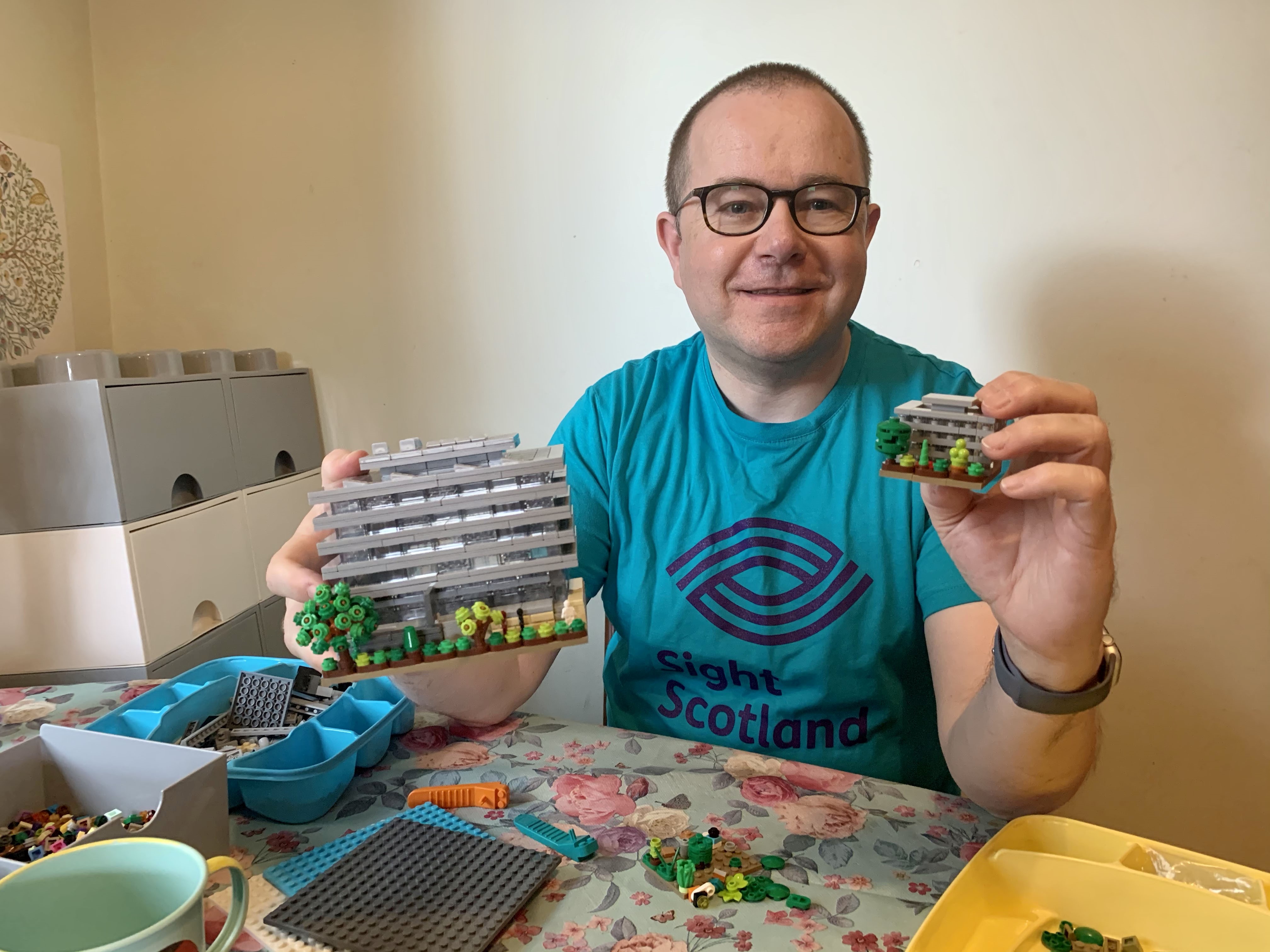 Fundraiser Stewart Lamb Cromar Lego Sight for Sight challenge 4 Fundraiser Stewart Lamb Cromar wears Lego t-shirt and holds Lego Main Library builds