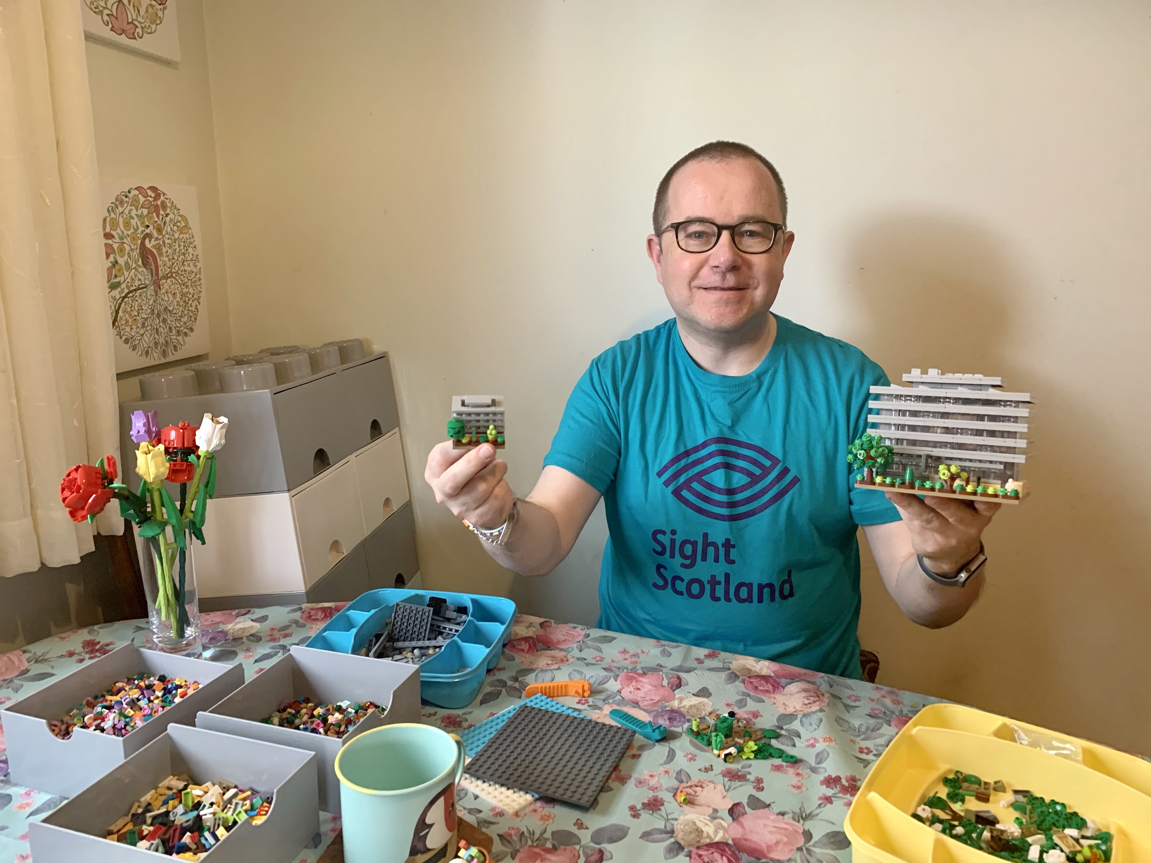 Fundraiser Stewart Lamb Cromar Lego Sight for Sight challenge 6 Fundraiser Stewart Lamb Cromar wears Lego t-shirt and holds Lego Main Library builds