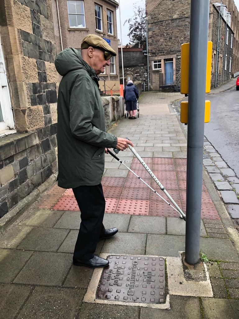 Veteran David Murray walking with long cane 1 Veteran David Murray stands with his long cane at a road crossing