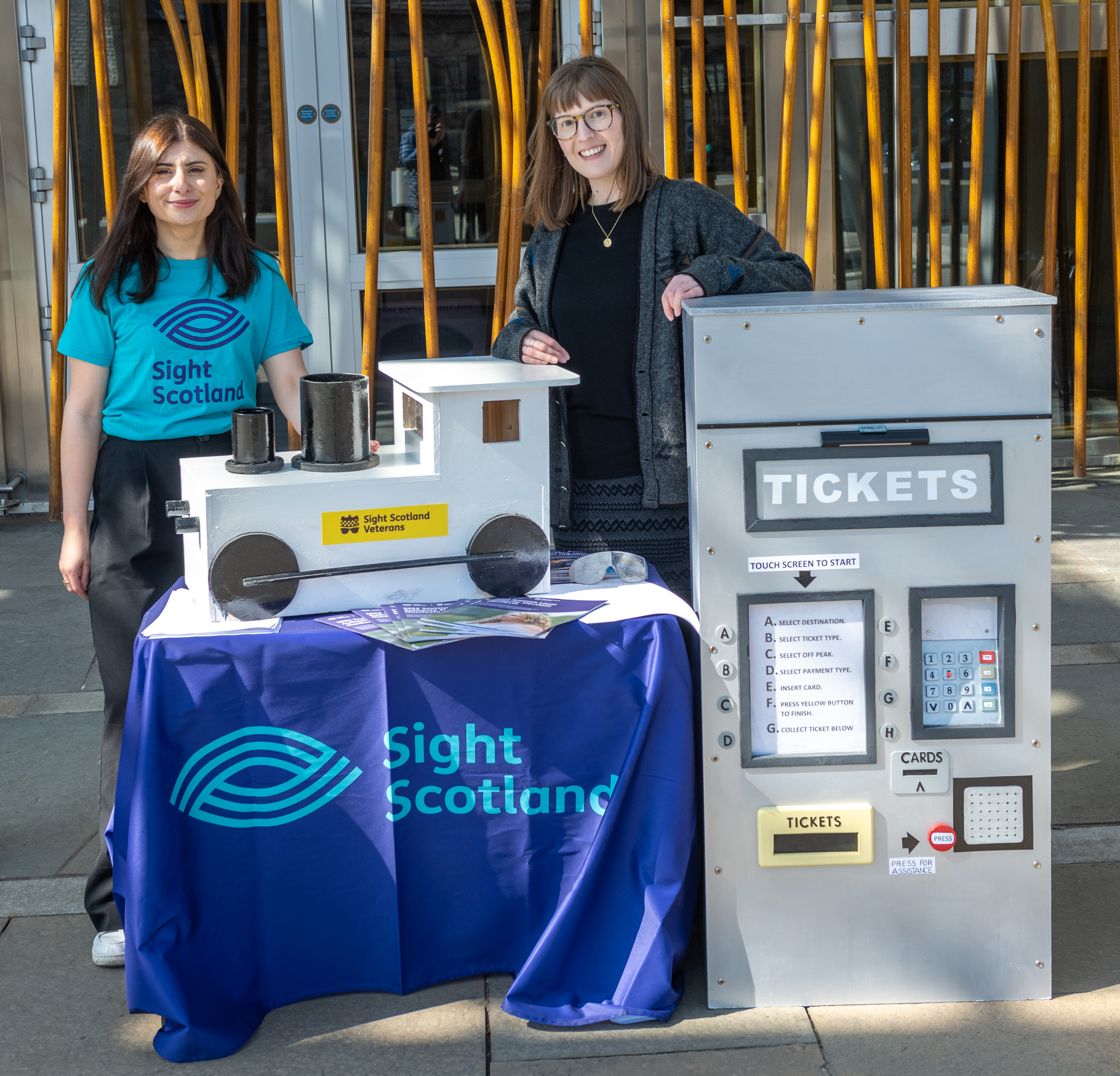 sight scotland team member standing behind ticket machine and train prop made for the campaign launch by sight scotland veterans