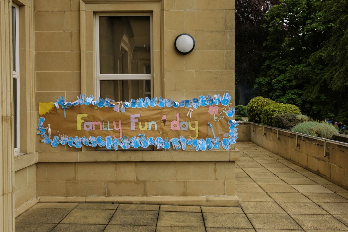 A colourful hand-made sign on the side of the school building reads 'Family Fun Day'
