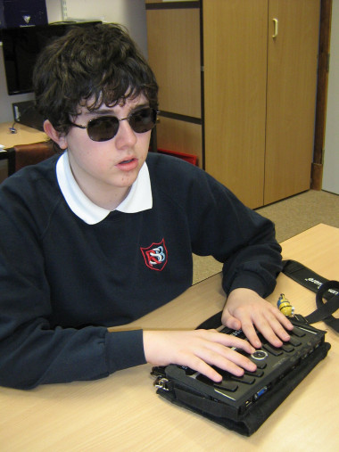 You know your child’s potential. We know vision. Let’s unlock your child’s potential together. Image shows Andrew typing braille