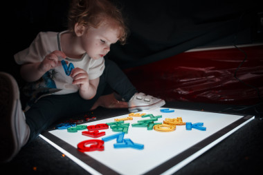 We offer learning opportunities and support for families, vital to every child with visual impairments and other complex needs during their earliest years of development. Image shows baby looking at letters. Early Years group