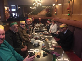 Veterans sit around a table wearing their Christmas hats before they enjoy their Christmas lunch