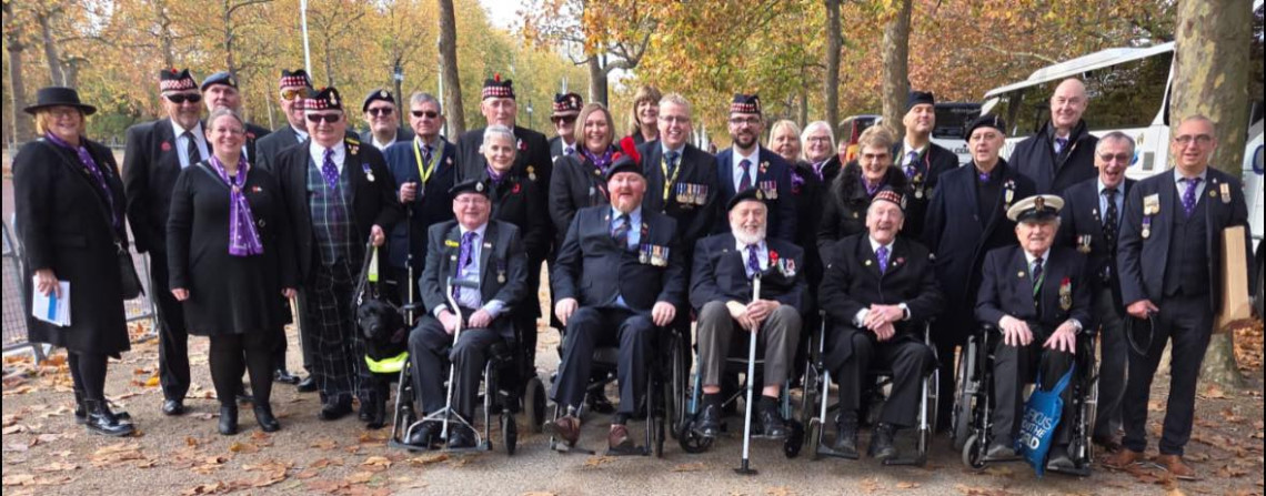 A group from Sight Scotland Veterans standing together in smart clothes and military uniform ready to march in the Remembrance Sunday Cenotaph Parade in London.