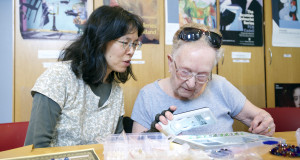 Art volunteer supports veteran using magnifier in Linburn Centre art room