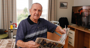 A care home resident at Jenny's Well reads a newspaper