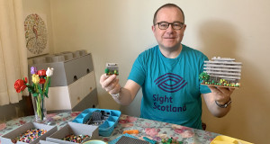 Fundraiser Stewart Lamb Cromar wears Lego t-shirt and holds Lego Main Library builds