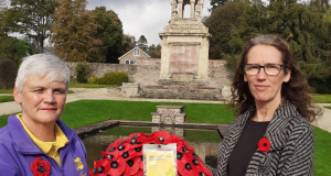 Outreach Workers Allison West and Gail Pringle holding a poppy wreath together in front of the Helensburgh War Memorial
