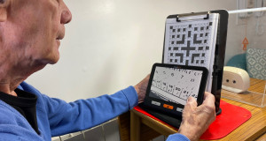 Veteran Henry Tyrell using electronic magnifier to read his Code Words puzzles