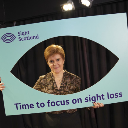 Nicola Sturgeon poses with a Sight Scotland selfie frame that says 'time to focus on sight loss'