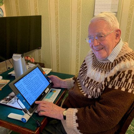 Veteran with sight loss reads magazine with Optelec Traveller HD video magnifier