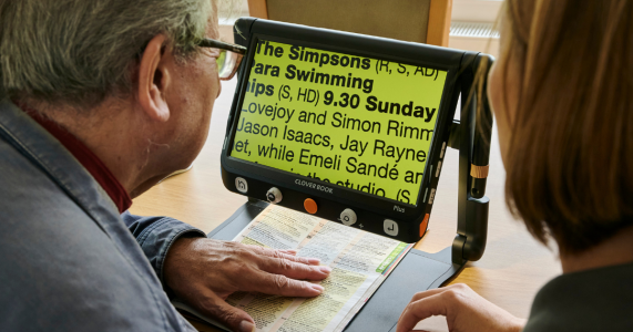 Magnifier Large Print Braille Week A man uses a magnifier to enlarge and read the text of his magazine